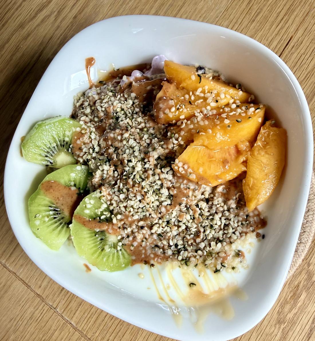 Peach Kiwi Gold Bowl: Pfirsichspalten und Kiwi auf goldenem Kurkuma-Porridge mit Hanfsamen